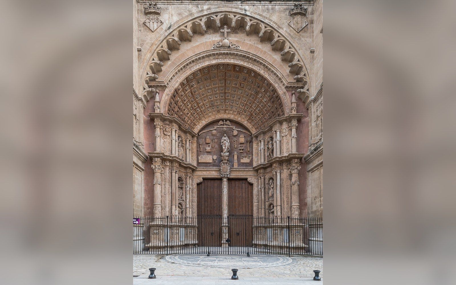Ornate stone archway framing a wooden cathedral doorway with carved statues above
