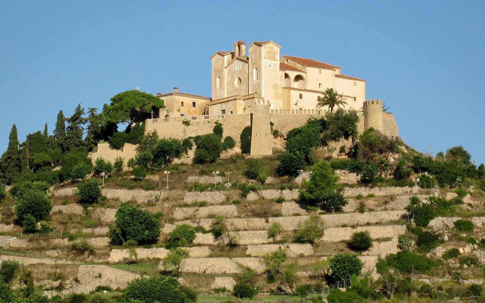 Hilltop sanctuary with twin bell towers rises above stone terraces and cypress trees