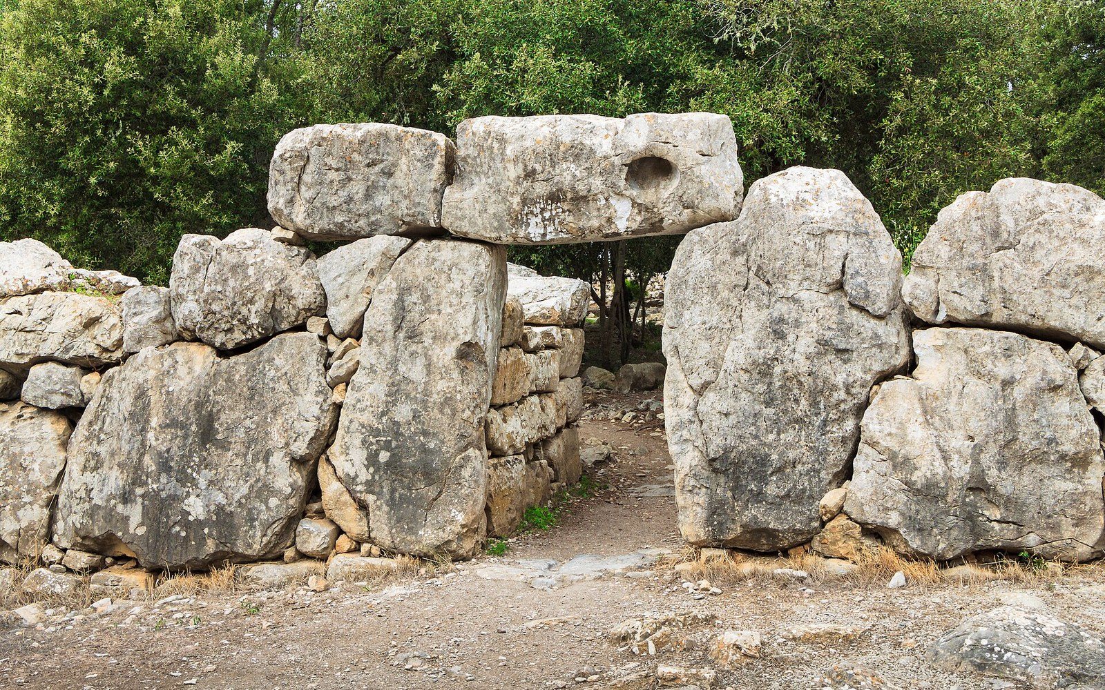 Massive stone lintel rests atop upright megaliths forming a doorway in a cyclopean wall