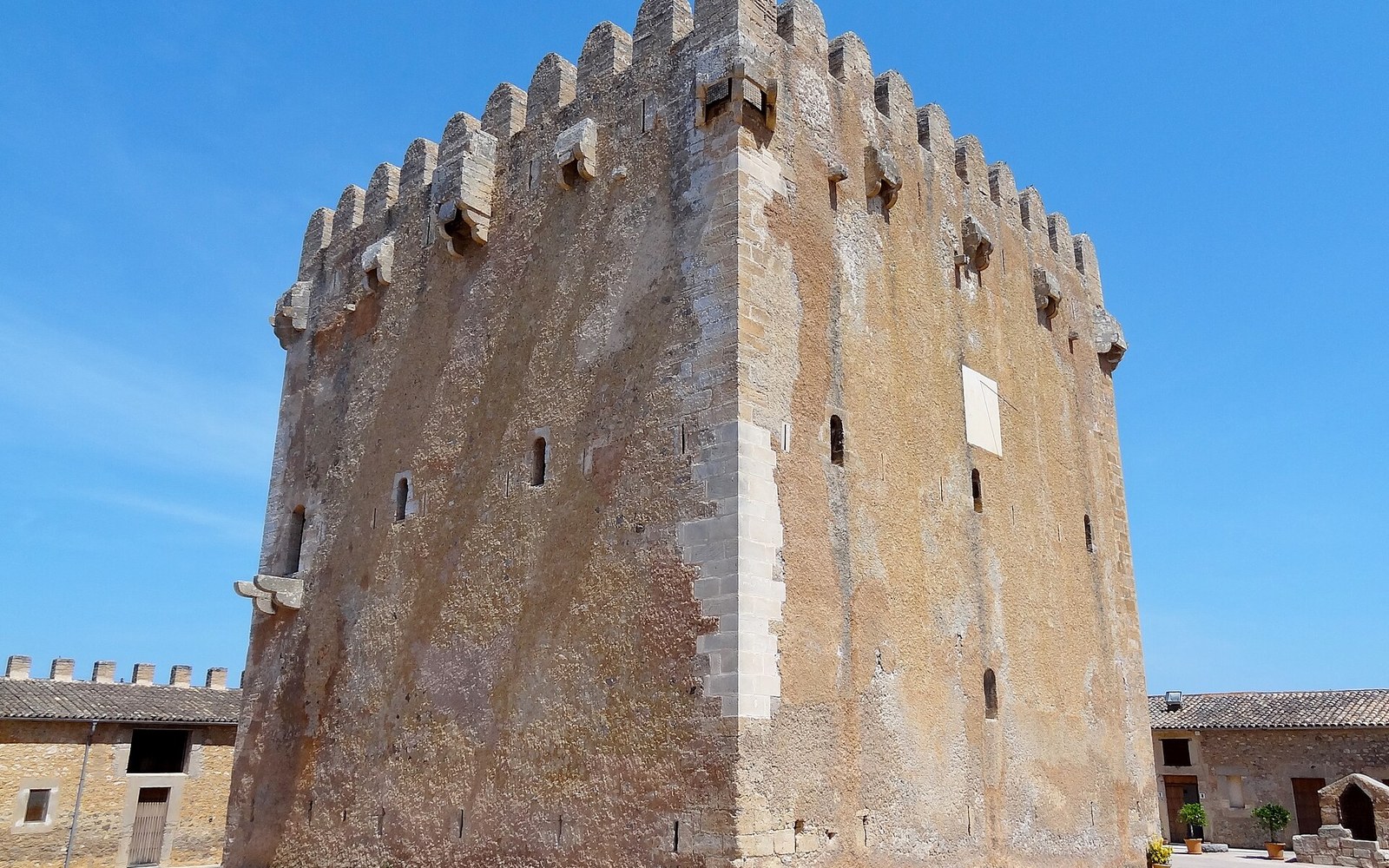 Stone keep of Torre de Canyamel with battlements against a clear blue sky